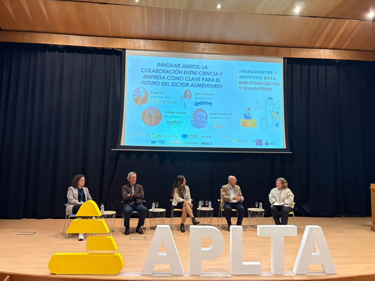 Mesa redonda en el escenario del auditorio, con el título de la sesión proyectado en la pantalla