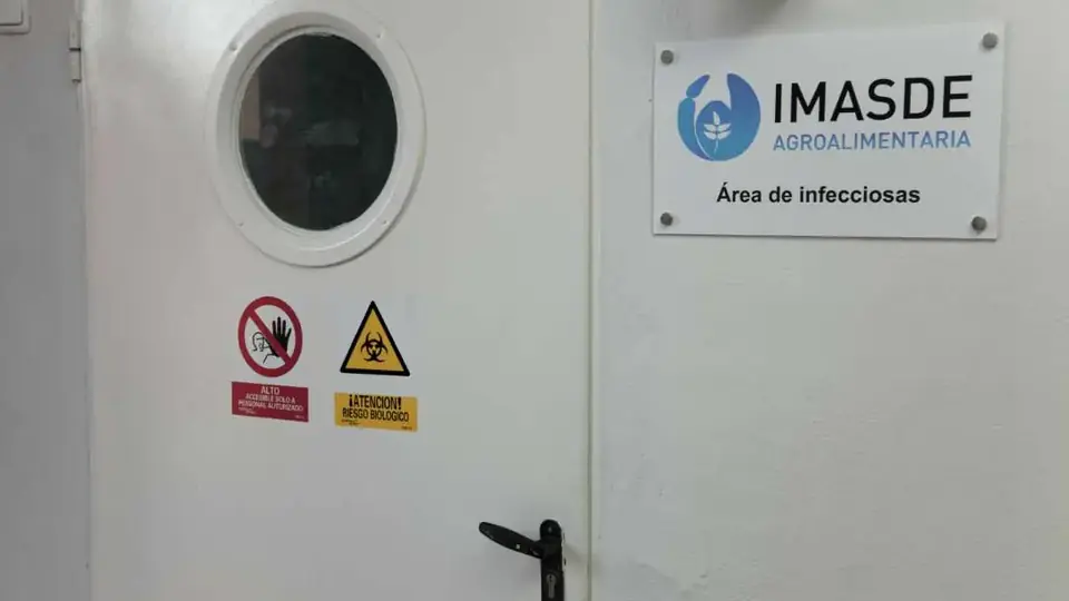 Puerta de acceso al área de infecciones con señalización de riesgo biológico